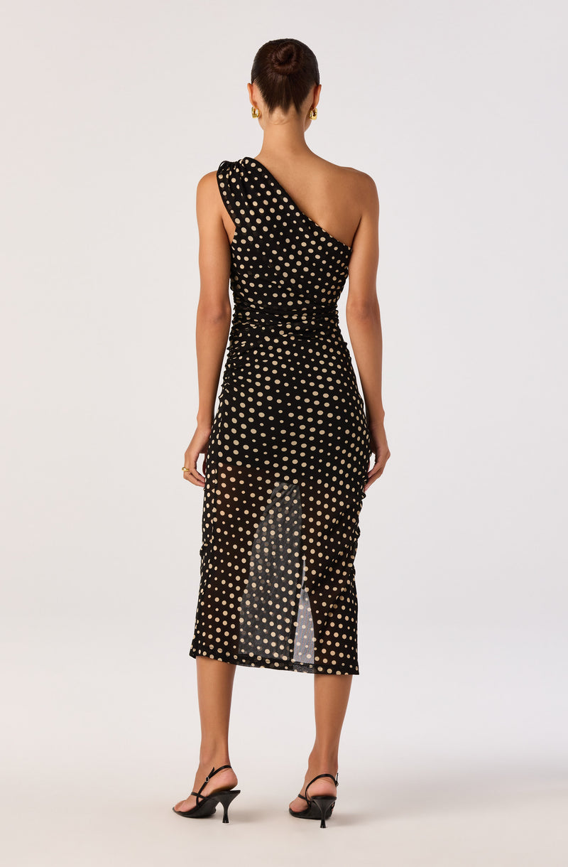 Black midi dress with white polka dots, one-shoulder design, and front slit.