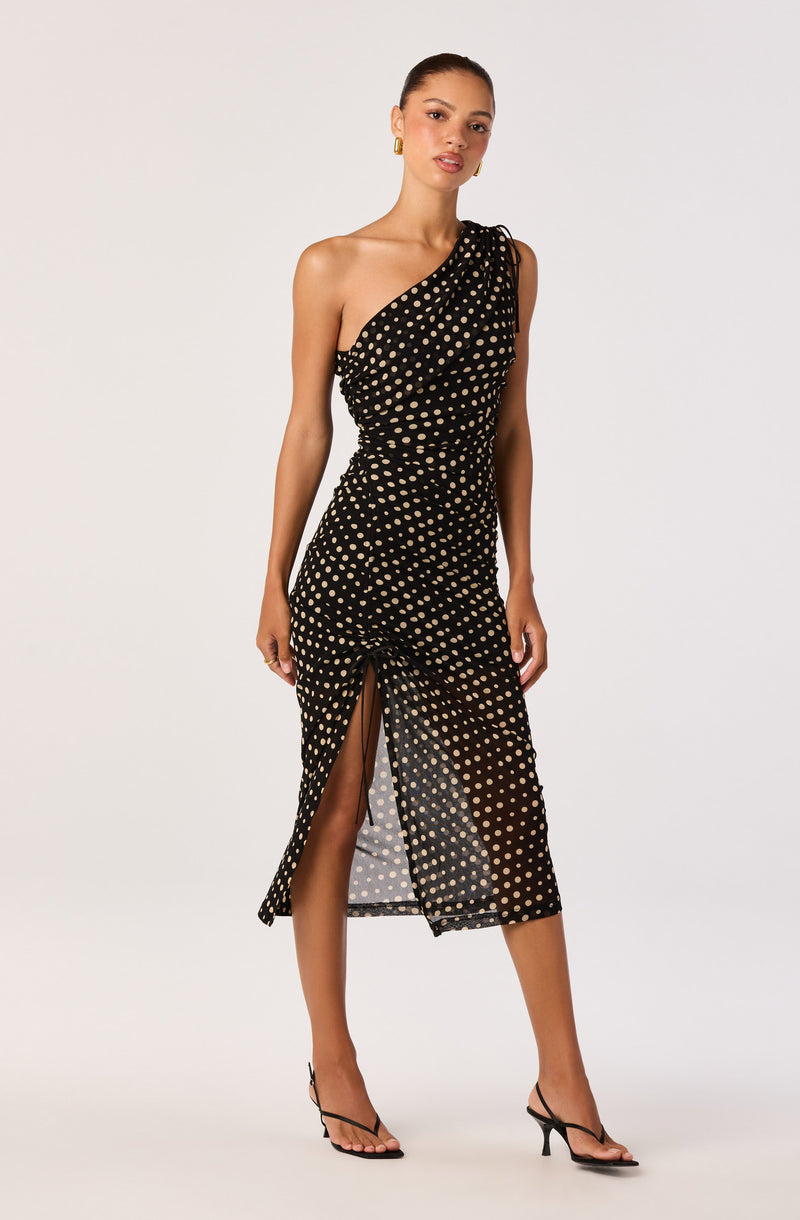Black dress with beige polka dots, one shoulder style, thigh-high slit, midi length, and spaghetti strap detail.
