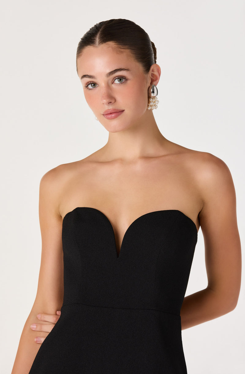 Woman wearing a black strapless dress with a heart-shaped neckline.