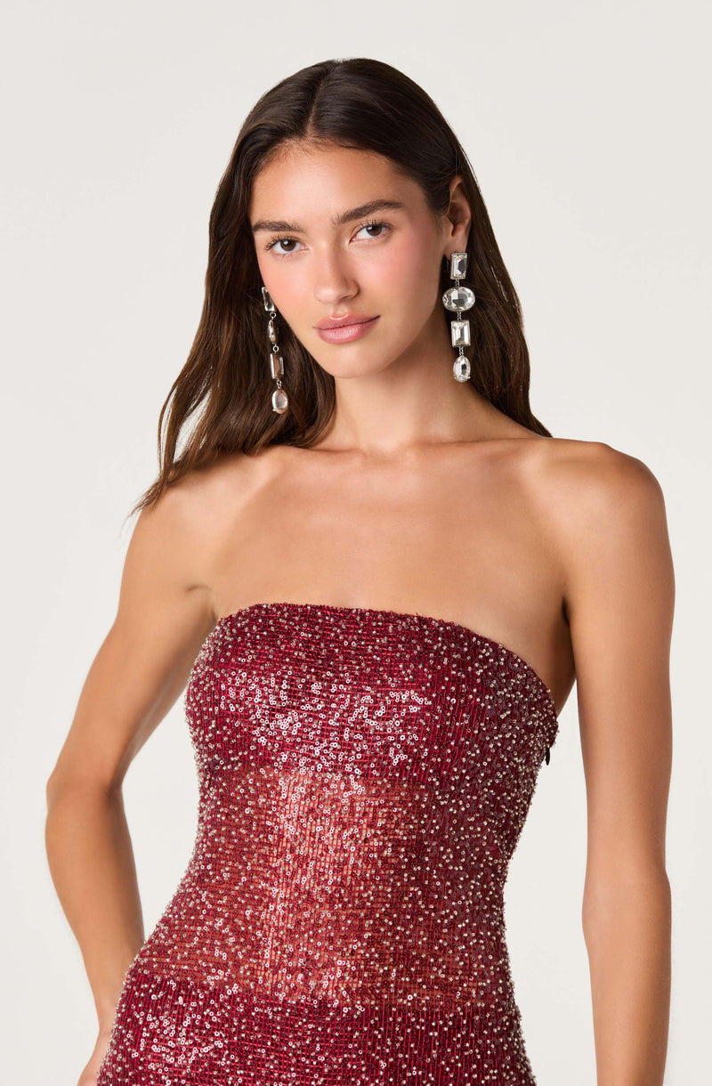 Woman in a strapless, red sequined gown with large, dangling silver earrings.