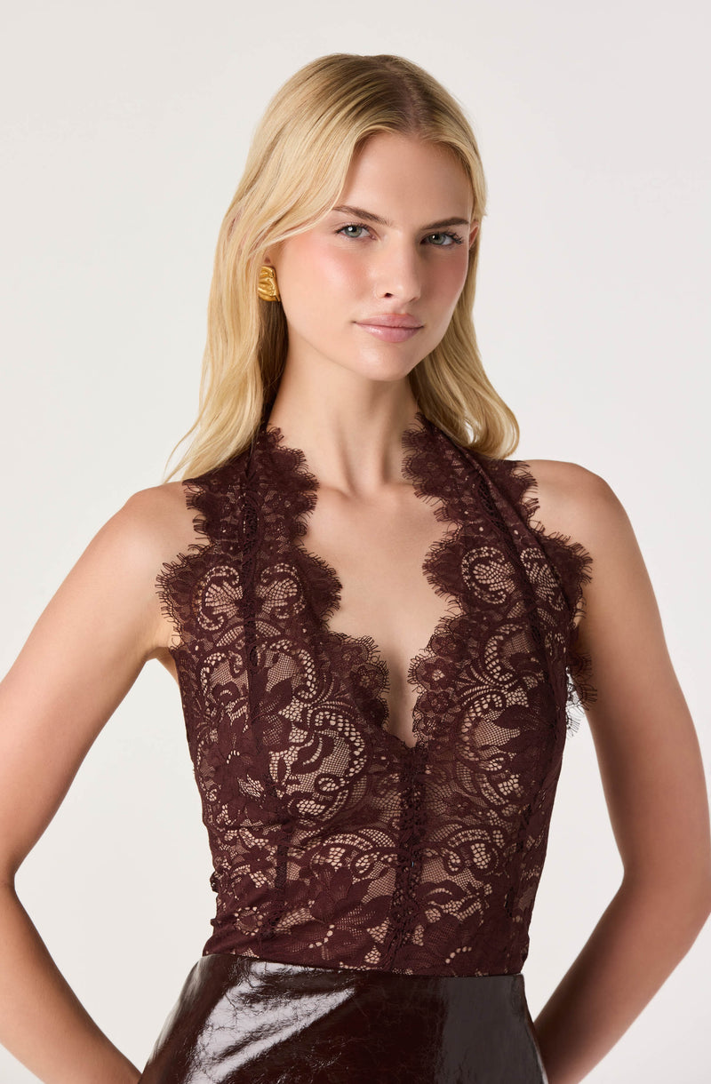 Woman wearing a sleeveless dark lace top with a deep neckline.