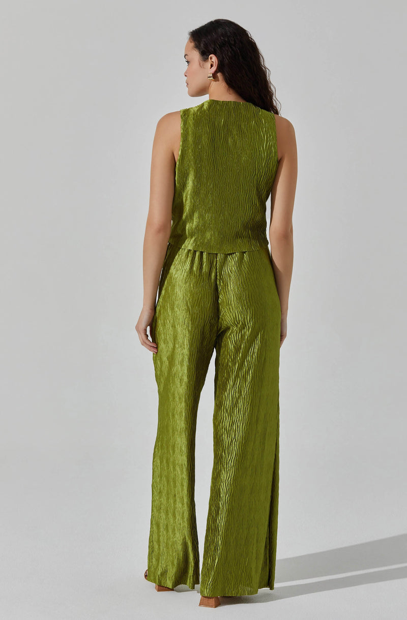 A woman is wearing a matching sleeveless top and wide-leg pants set in a shiny, textured lime green fabric. The top is fitted at the waist with a straight cut, while the pants are high-waisted with a relaxed fit and extend down to the floor.