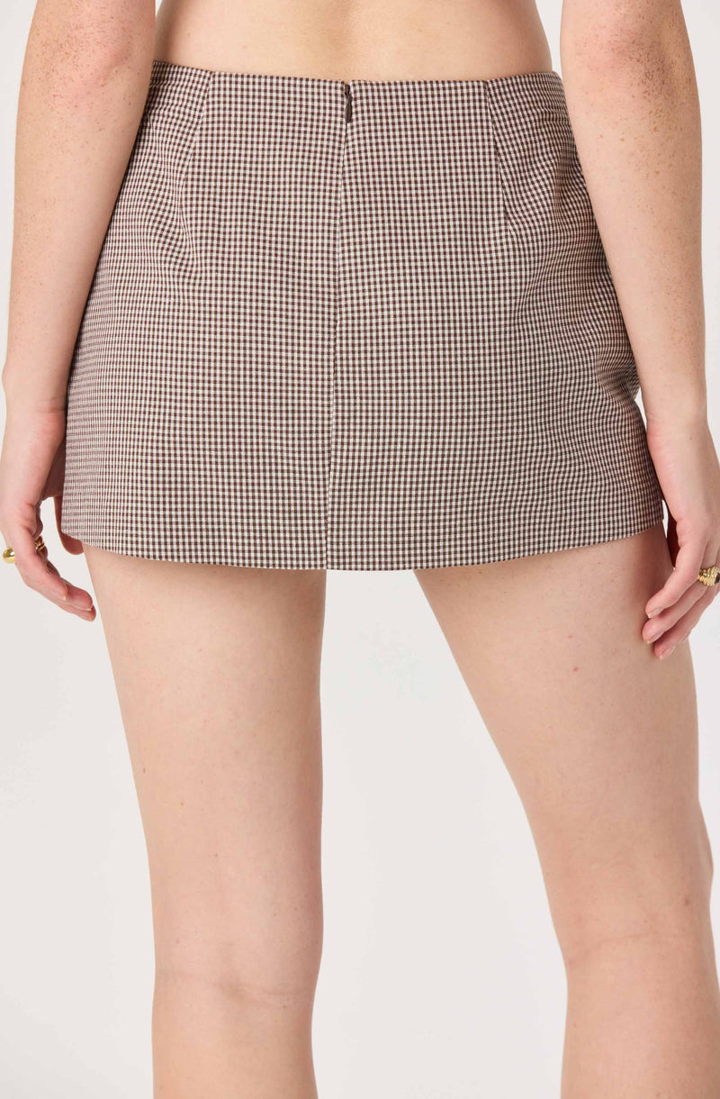 Woman wears high-waisted shorts with small checkered pattern in brown and white.