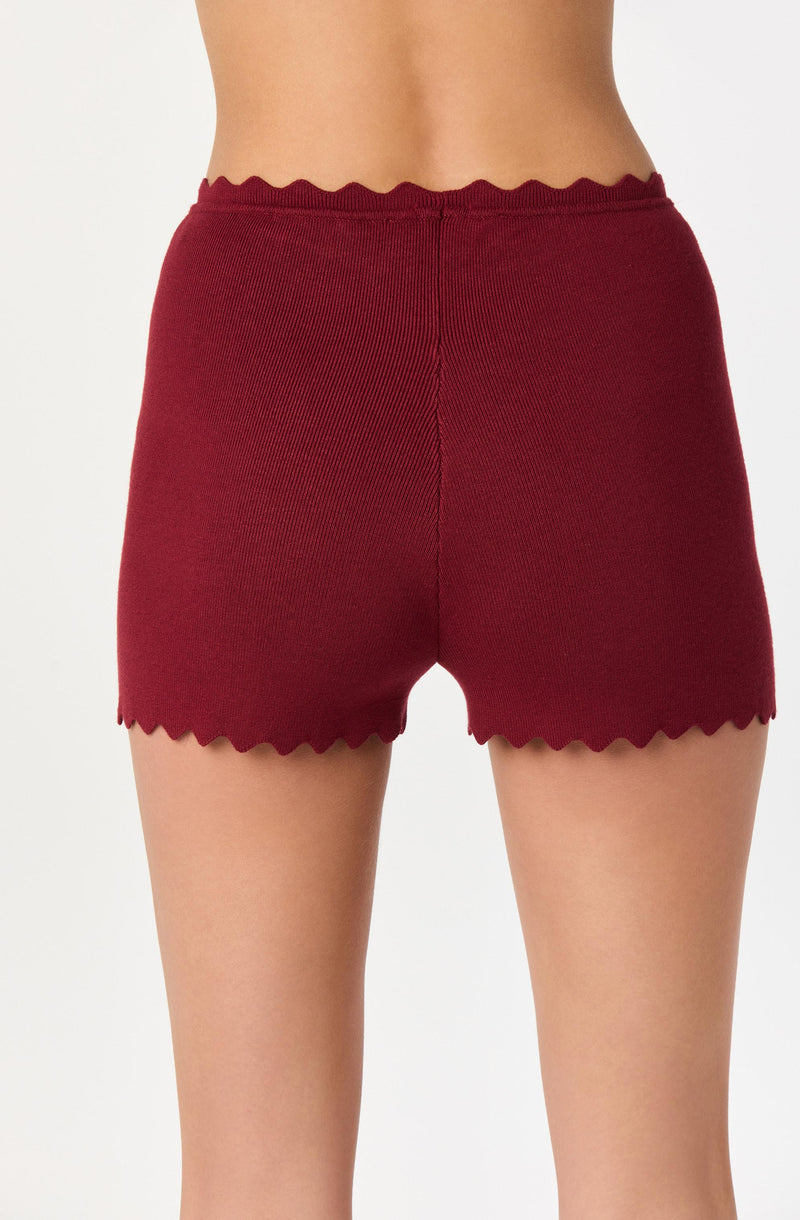 A person is wearing high-waisted, red knit shorts with scalloped edges at the waistband and leg openings.