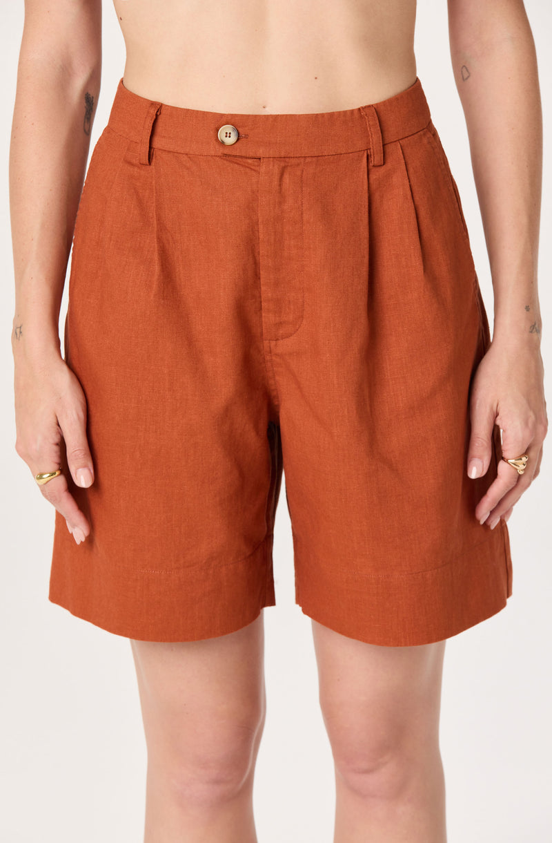 High-waisted orange shorts with pleats and a button closure.