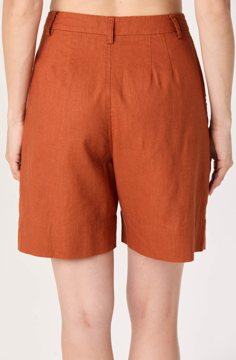 High-waisted rust-colored shorts with front pleats and belt loops.