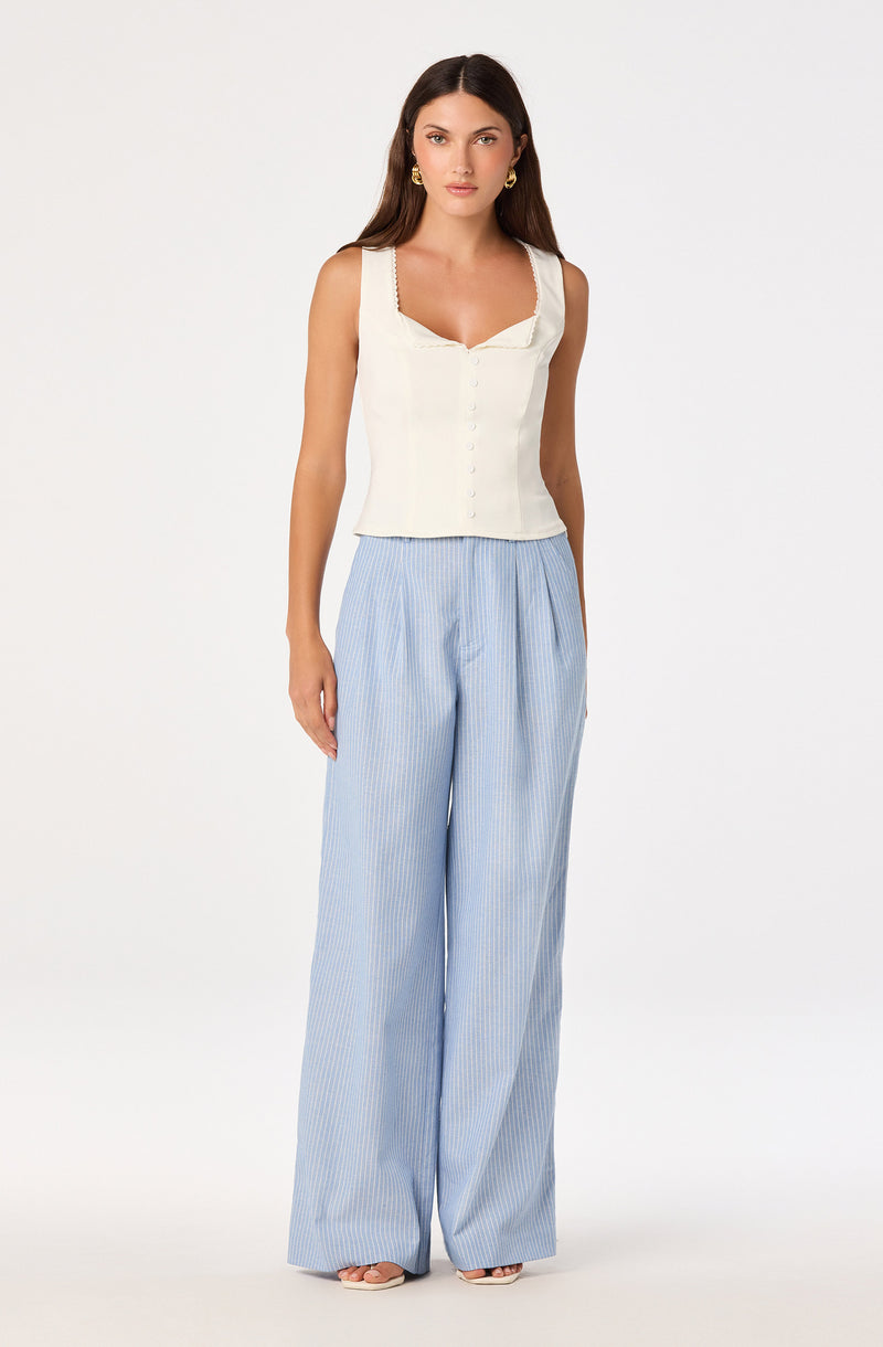 Cream sleeveless top with buttons and lace details, paired with high-waisted, wide-leg blue and white striped pants.