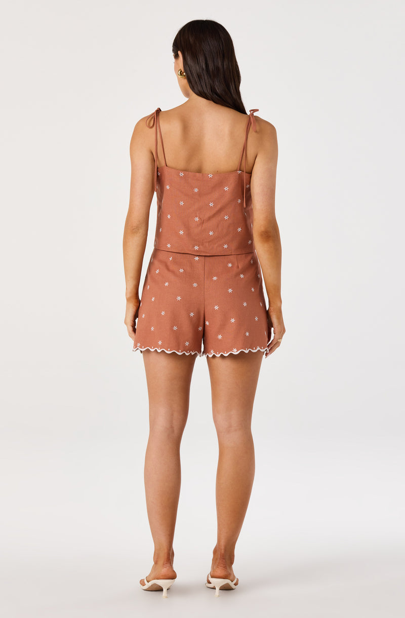 Pink sleeveless top and shorts set with small white floral patterns and scalloped edges.