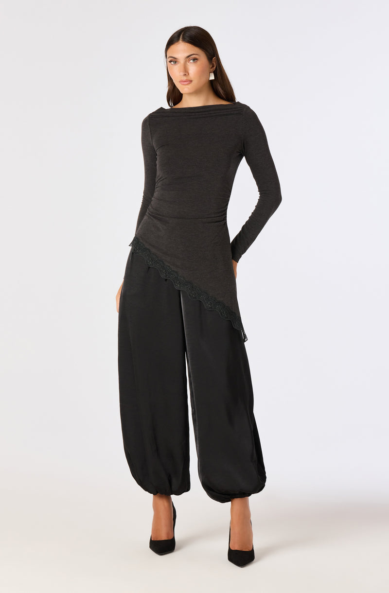 Woman in a fitted dark gray long-sleeve top with lace trim and wide black pants with elastic cuffs.