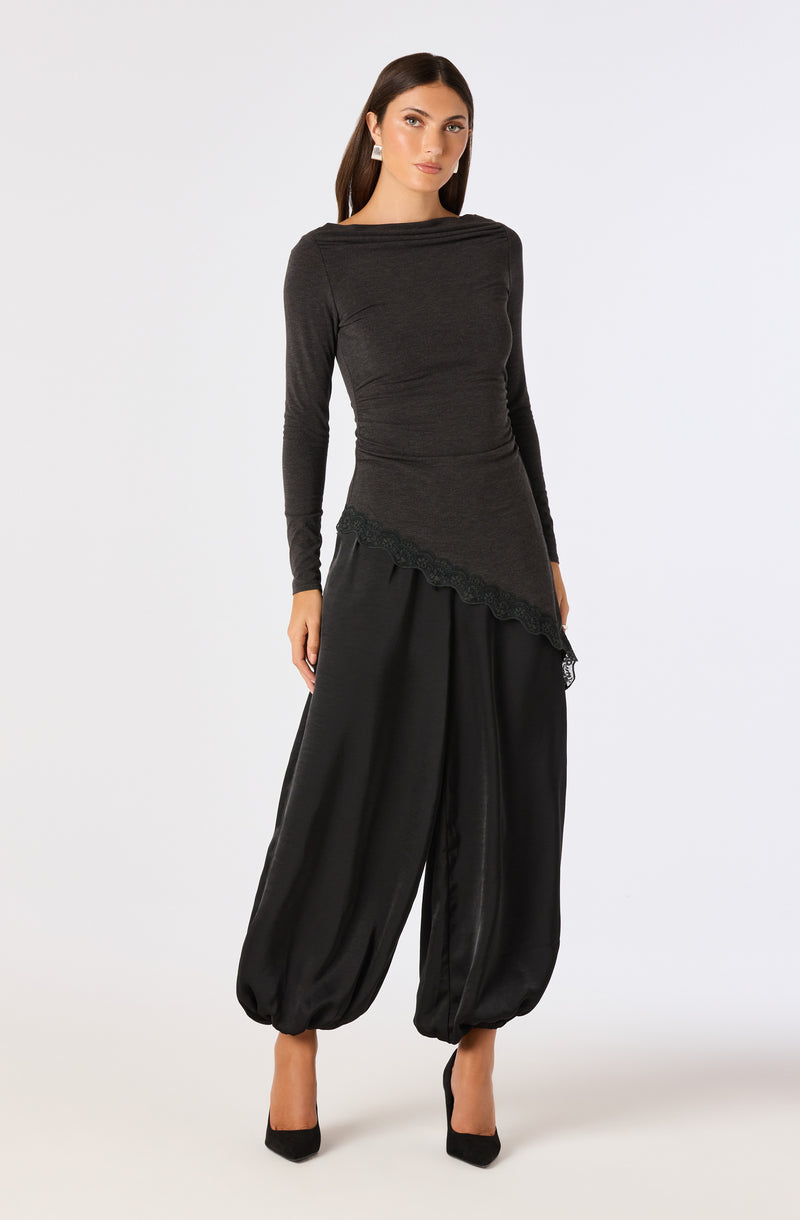 Woman wearing a fitted dark gray long-sleeve top and wide black harem pants with elastic cuffs.