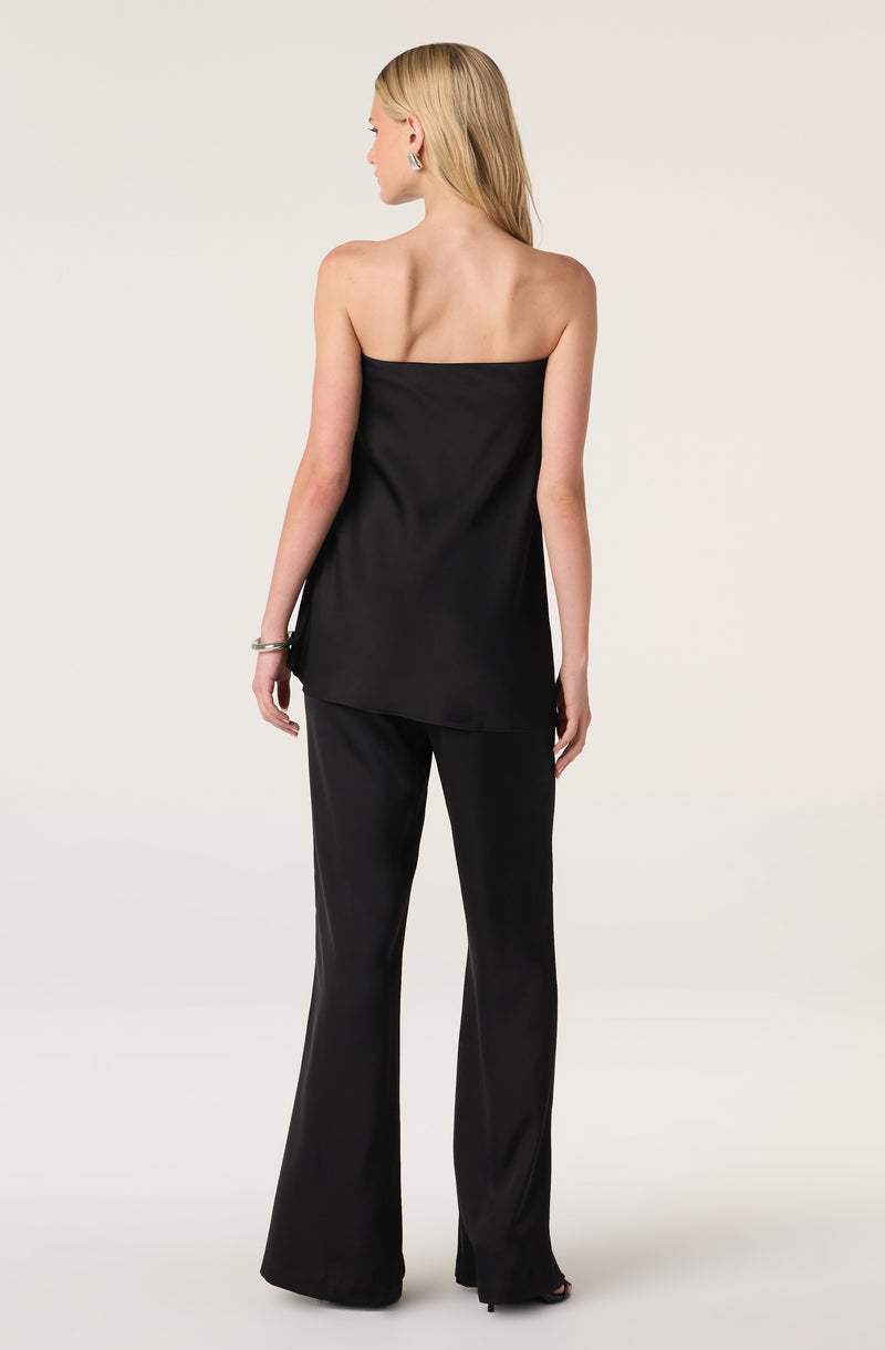 Woman in black strapless top and wide-leg pants, with blonde hair.