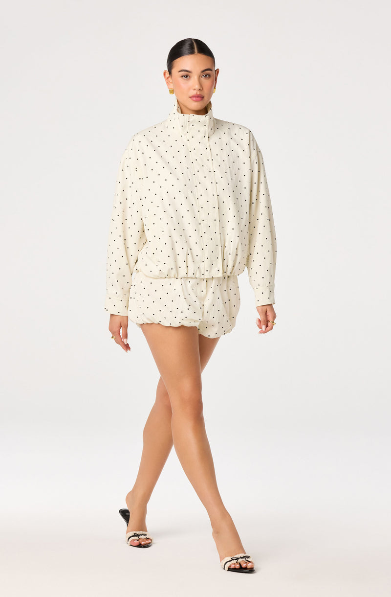 Woman in white polka dot jacket and matching shorts.