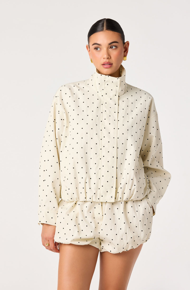 Woman wearing a cream-colored polka dot jacket and matching shorts, high collar, zip front.