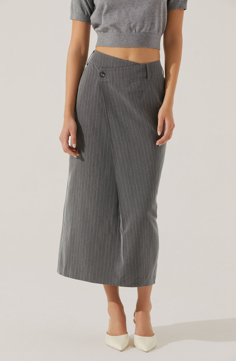 A person is wearing a cropped gray short-sleeve sweater and a high-waisted, gray, wide-leg skirt with thin white pinstripes. The skirt has a snap button and zipper closure on the side. They are also wearing white pointed-toe shoes.