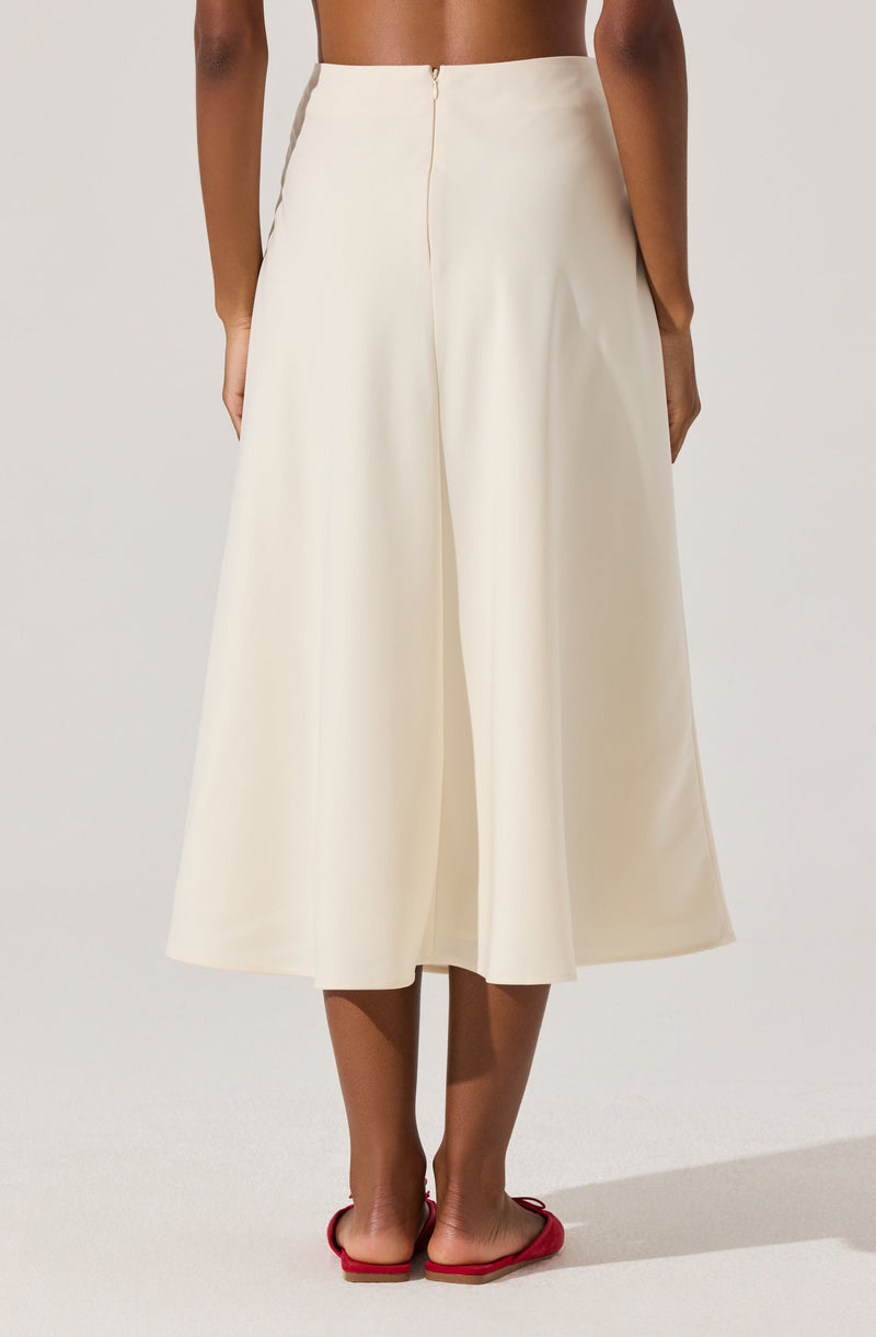 The image shows a person wearing a pair of high-waisted, wide-leg cream-colored pants that reach mid-calf length. The pants have a smooth, flowing fabric with a front zipper closure. The person is barefoot, wearing red flip-flops.
