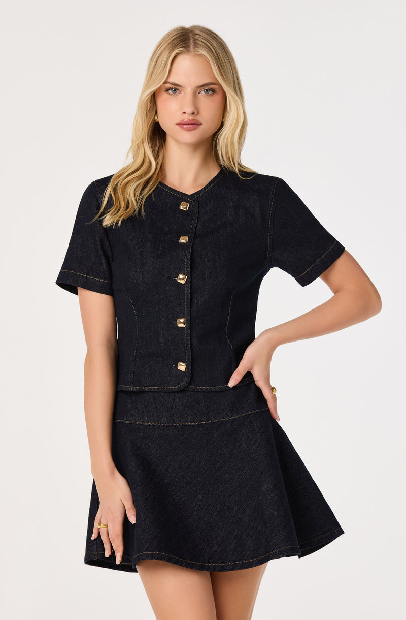 Woman wearing a black denim short-sleeve top and matching black denim skirt.
