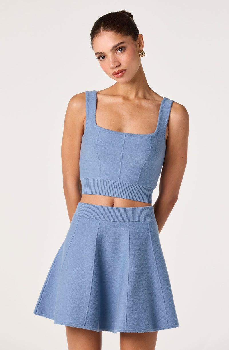 Light blue sleeveless knit crop top with wide straps and matching high-waisted flared skirt.