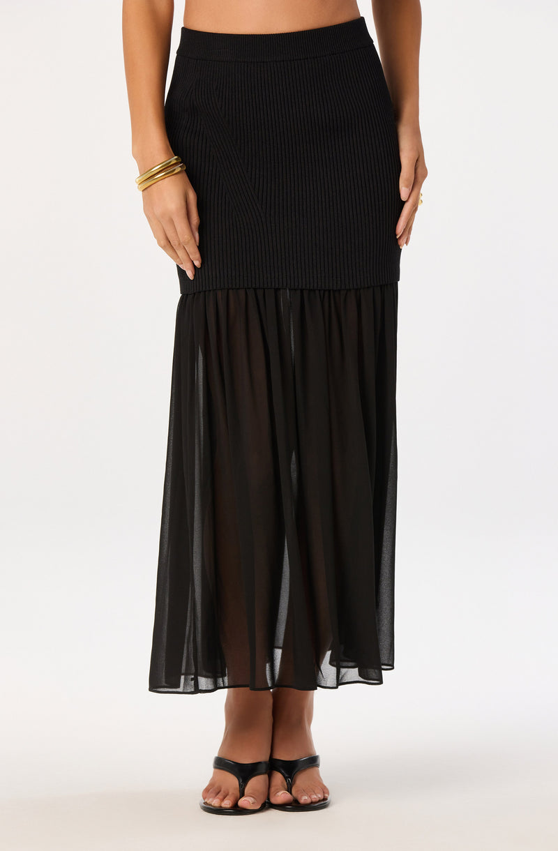 Black ribbed skirt with sheer black tulle overlay and black open-toe heels.