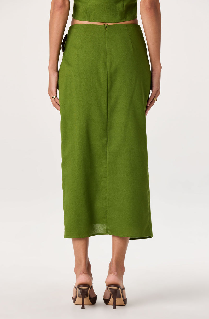 Woman wearing a green midi skirt with a back zipper and side pocket details.