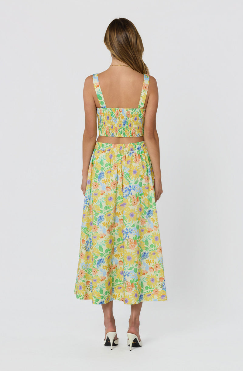 Woman wearing a colorful, floral two-piece outfit with a crop top and wide-leg skirt.