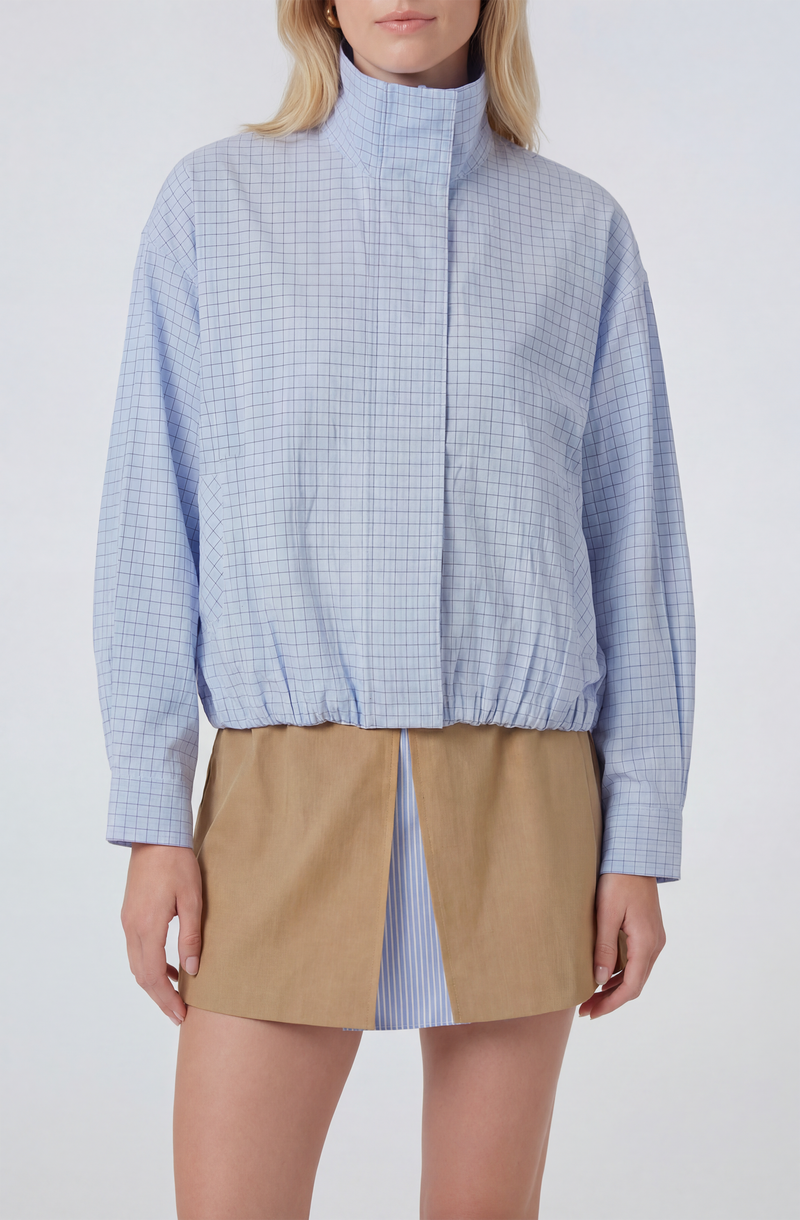 Light blue checkered jacket with a high collar and elastic waist, paired with a beige skirt.