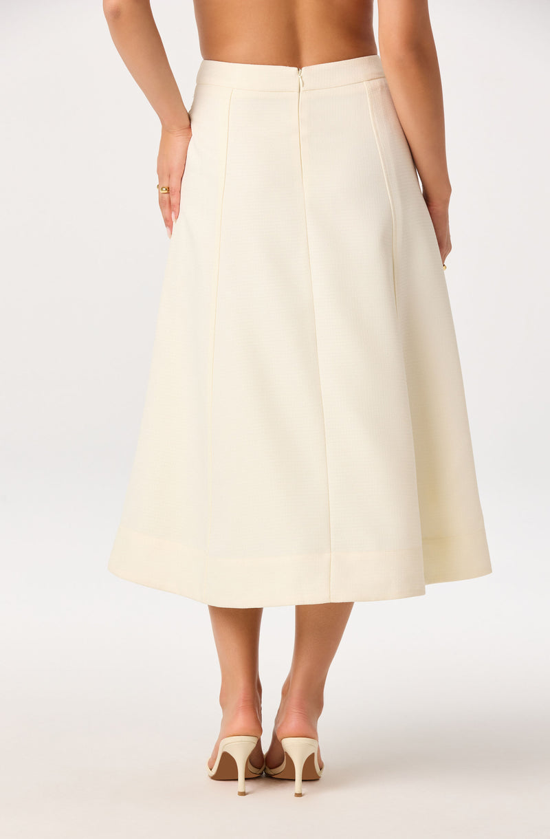 High-waisted cream midi skirt with a back zipper and wide hem, paired with beige heels.