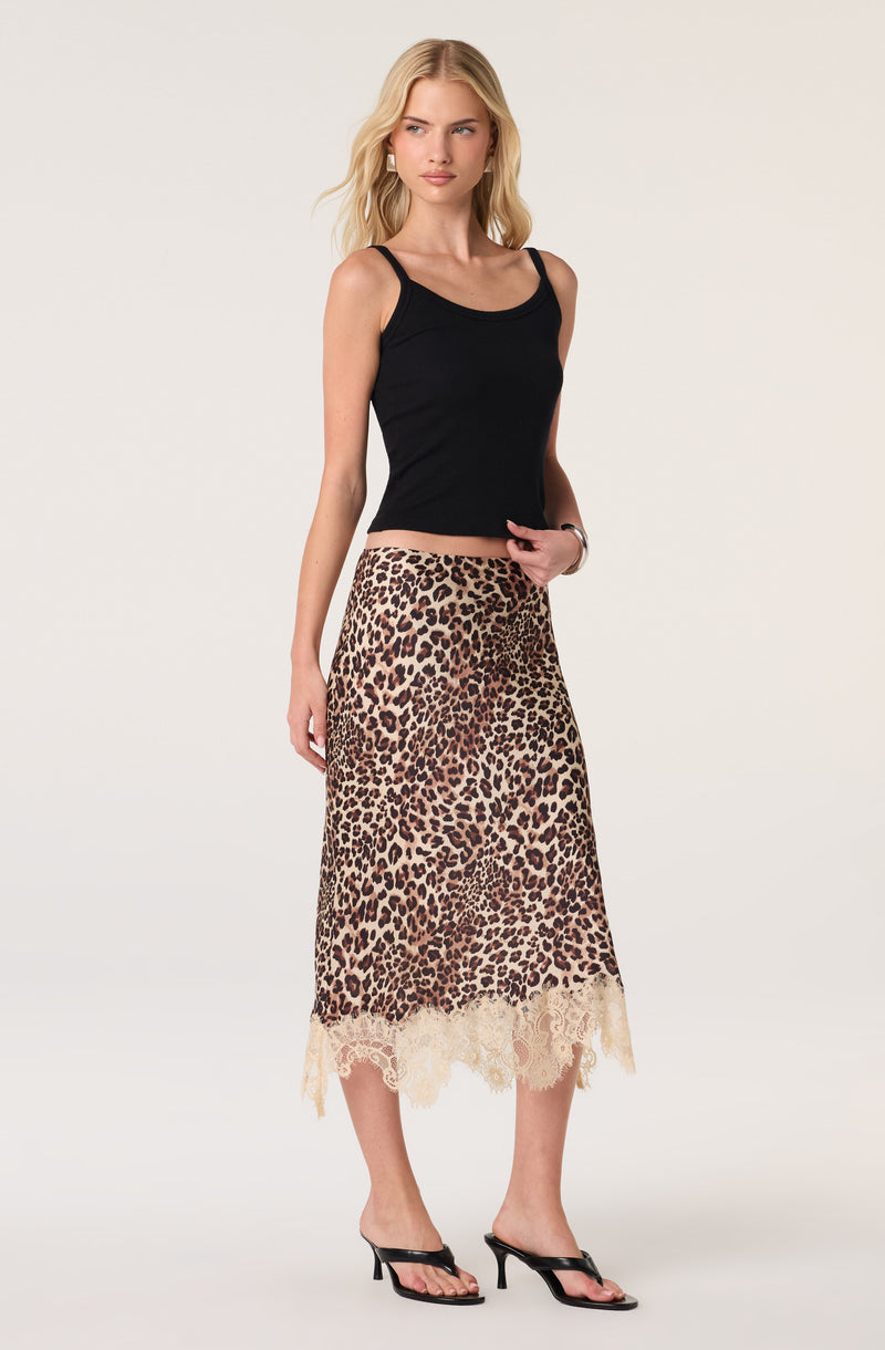 Woman in a black tank top and leopard print lace-trimmed skirt, black heeled sandals.