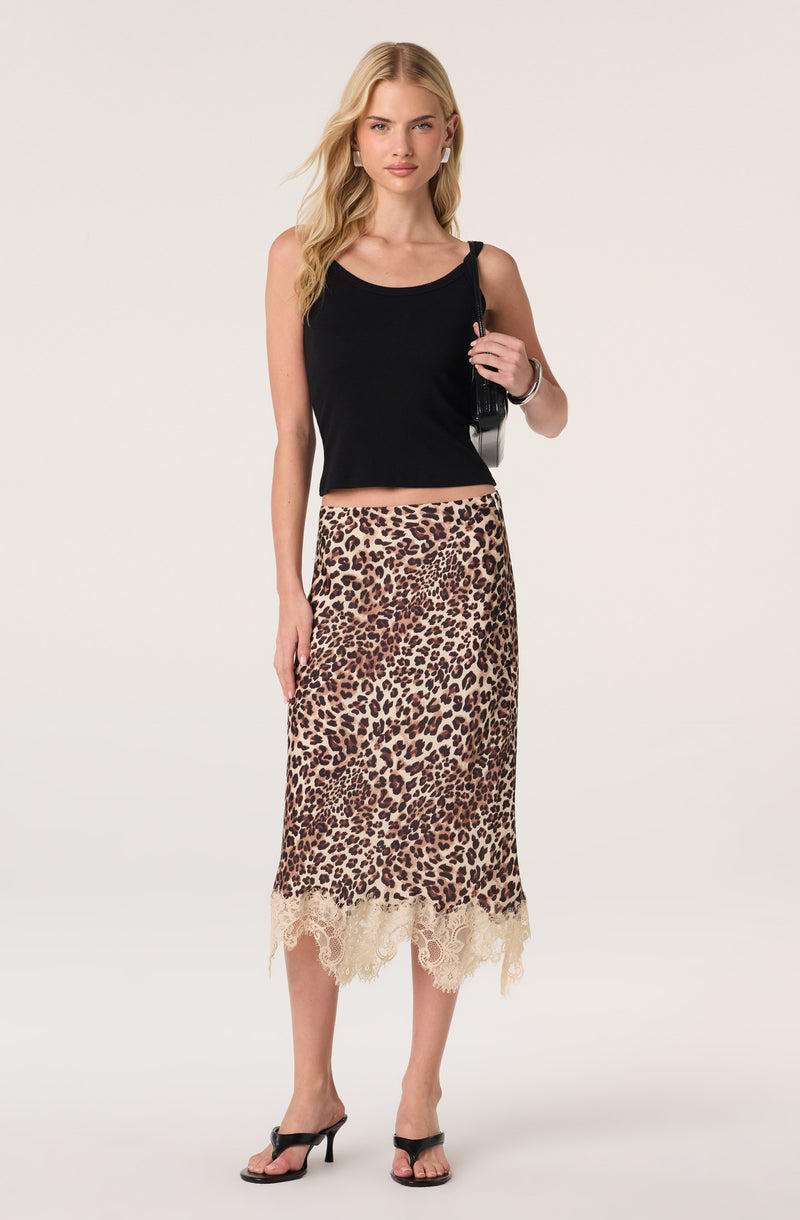 Woman wearing a black sleeveless top, leopard-print skirt with lace hem, and black high-heeled sandals.