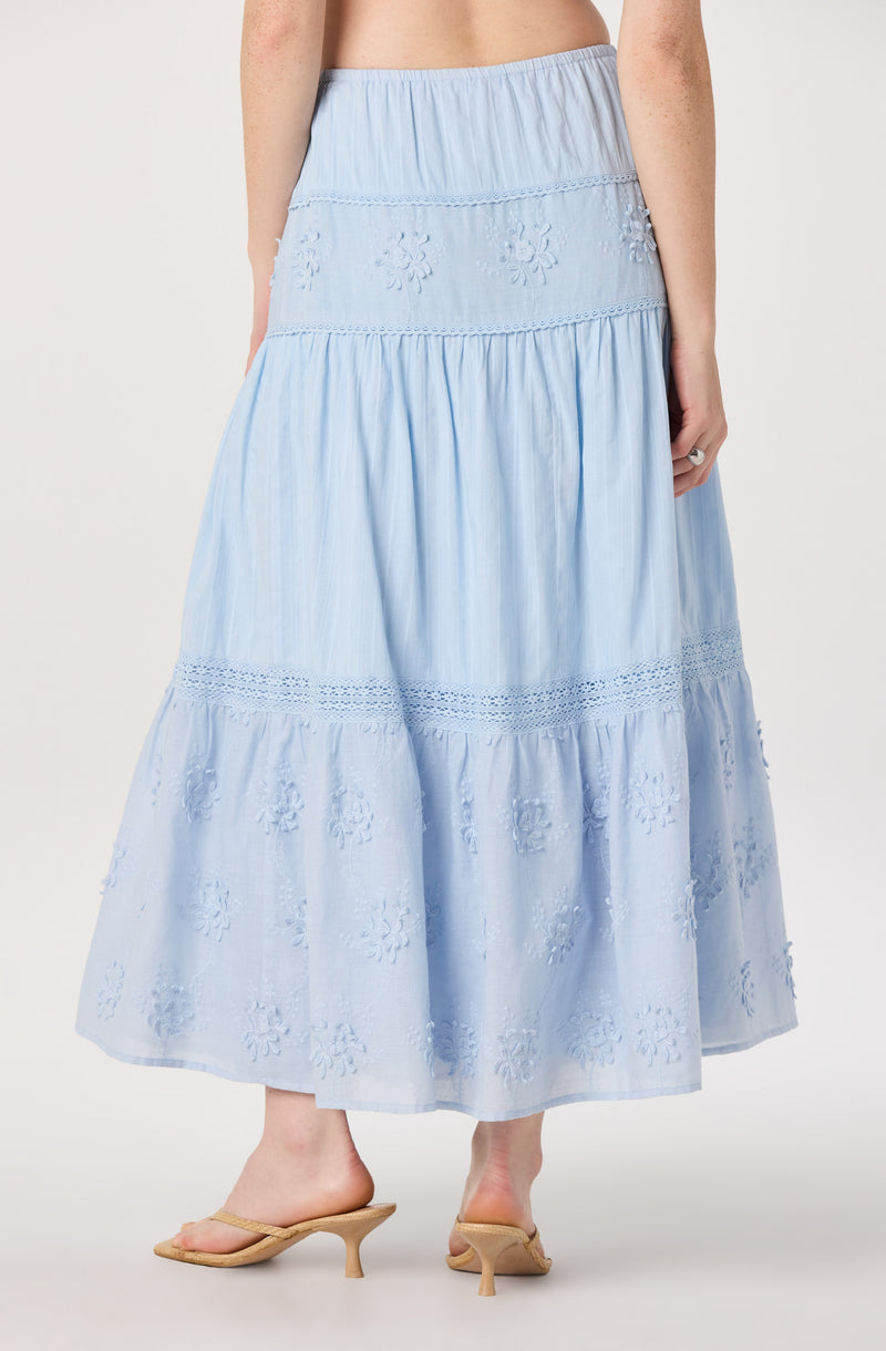Light blue, tiered maxi skirt with embroidered floral patterns and cutwork details.