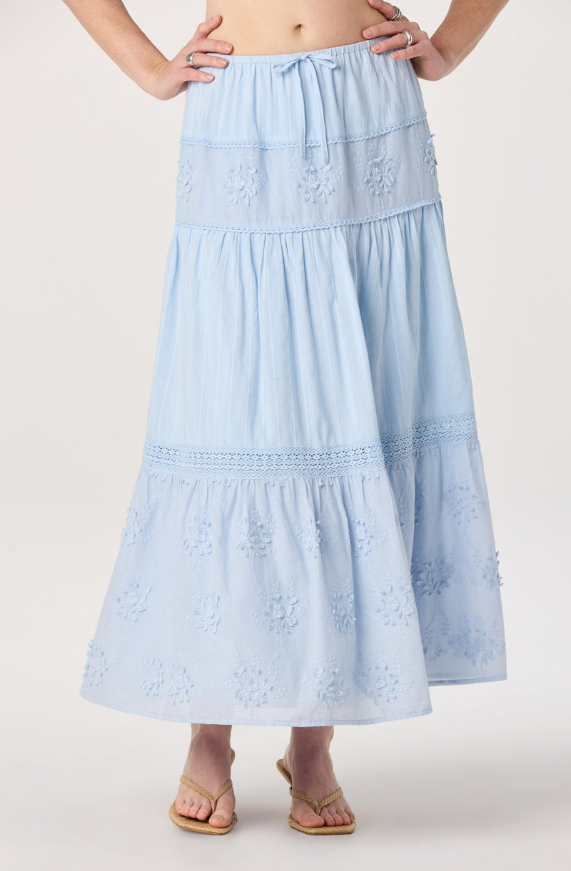 Light blue, tiered, embroidered maxi skirt with a drawstring waist and open-toed sandals.
