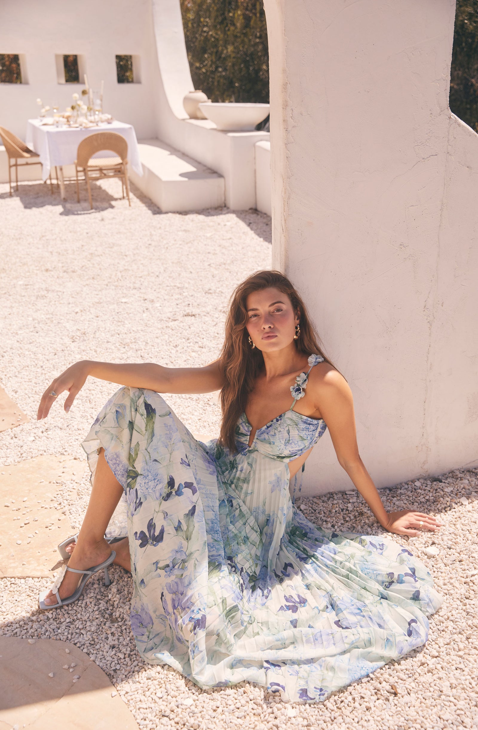 Woman wearing a light, flowy, floral sundress with thin shoulder straps and cut-out sides.