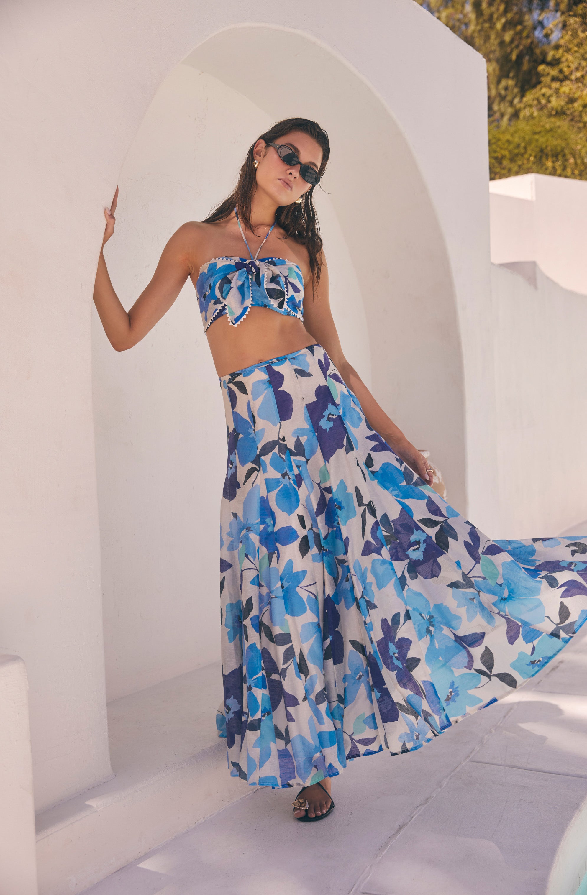 Woman wearing a strapless blue floral crop top and matching wide-leg skirt with a floral pattern.