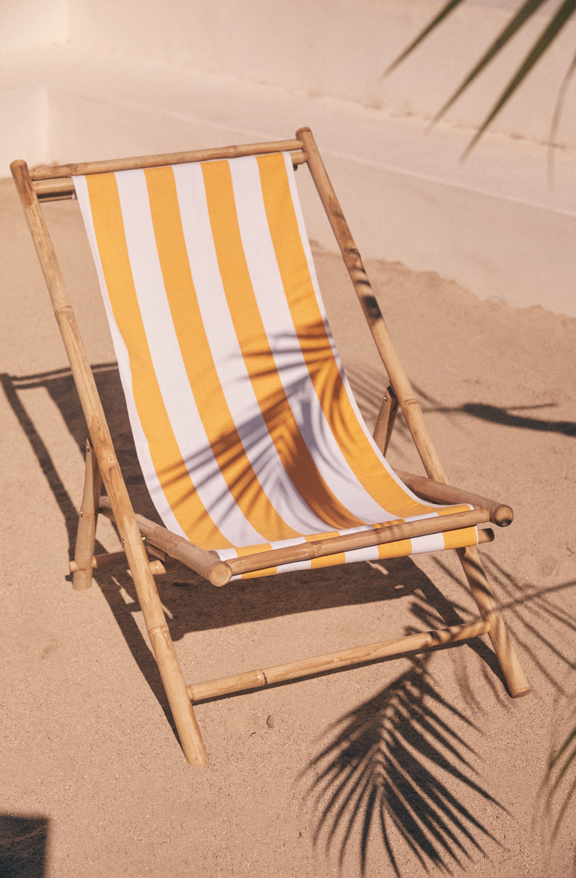 Yellow and white striped fabric on a wooden beach chair.