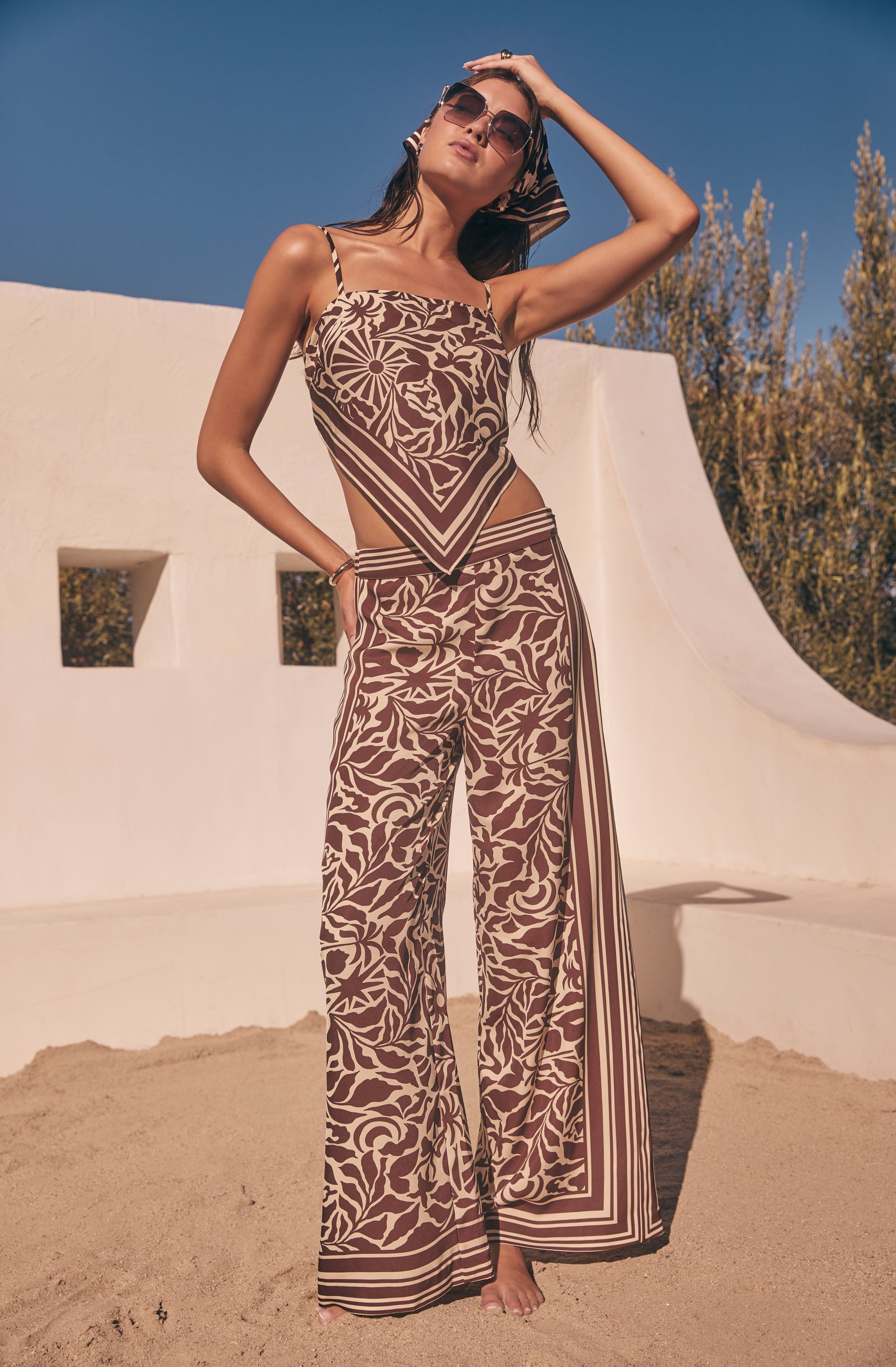 Woman in brown and beige patterned sleeveless top and wide-leg matching pants with stripe accents.
