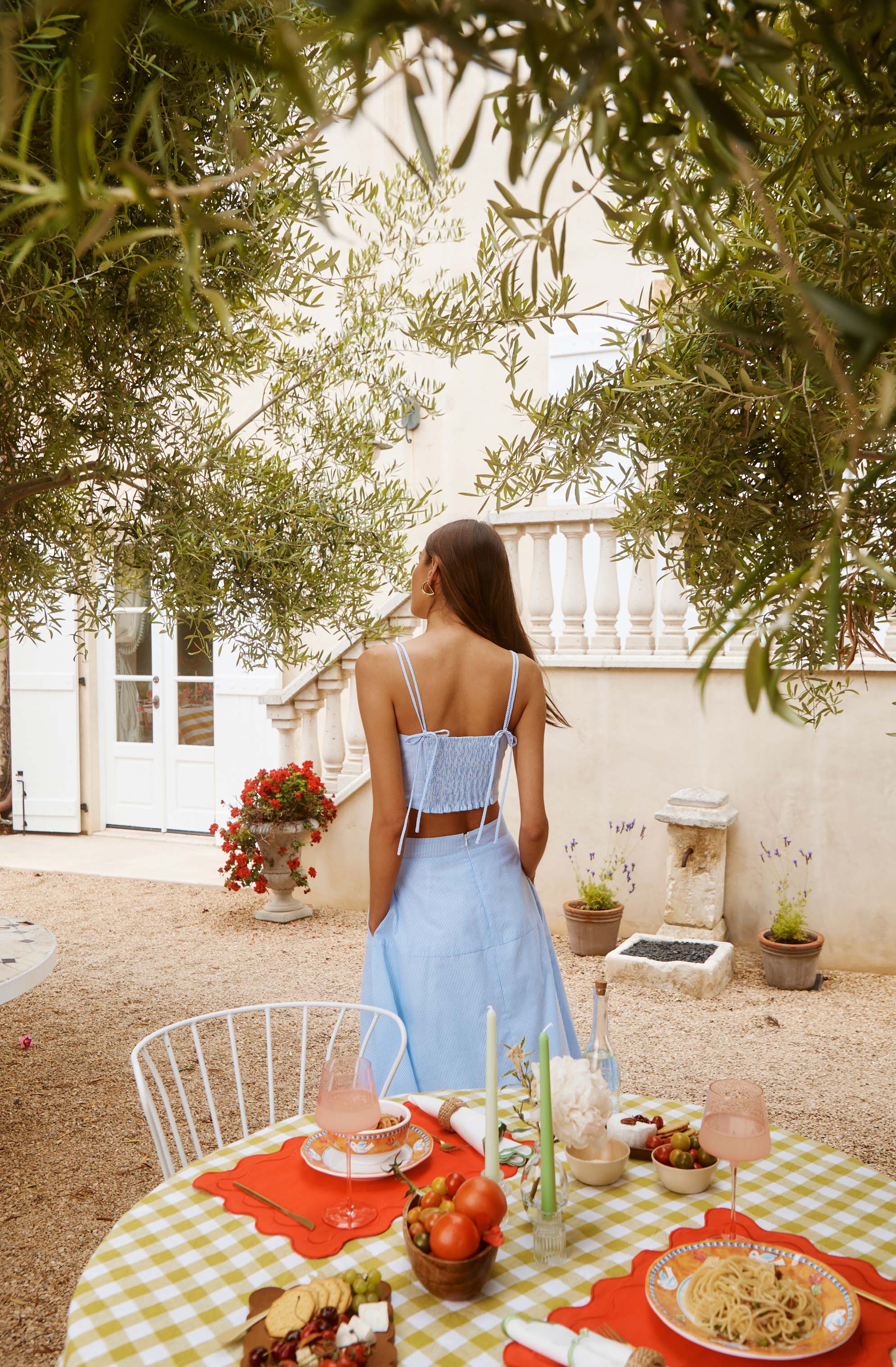 Woman in a light blue, sleeveless crop top and matching high-waisted skirt outdoors.