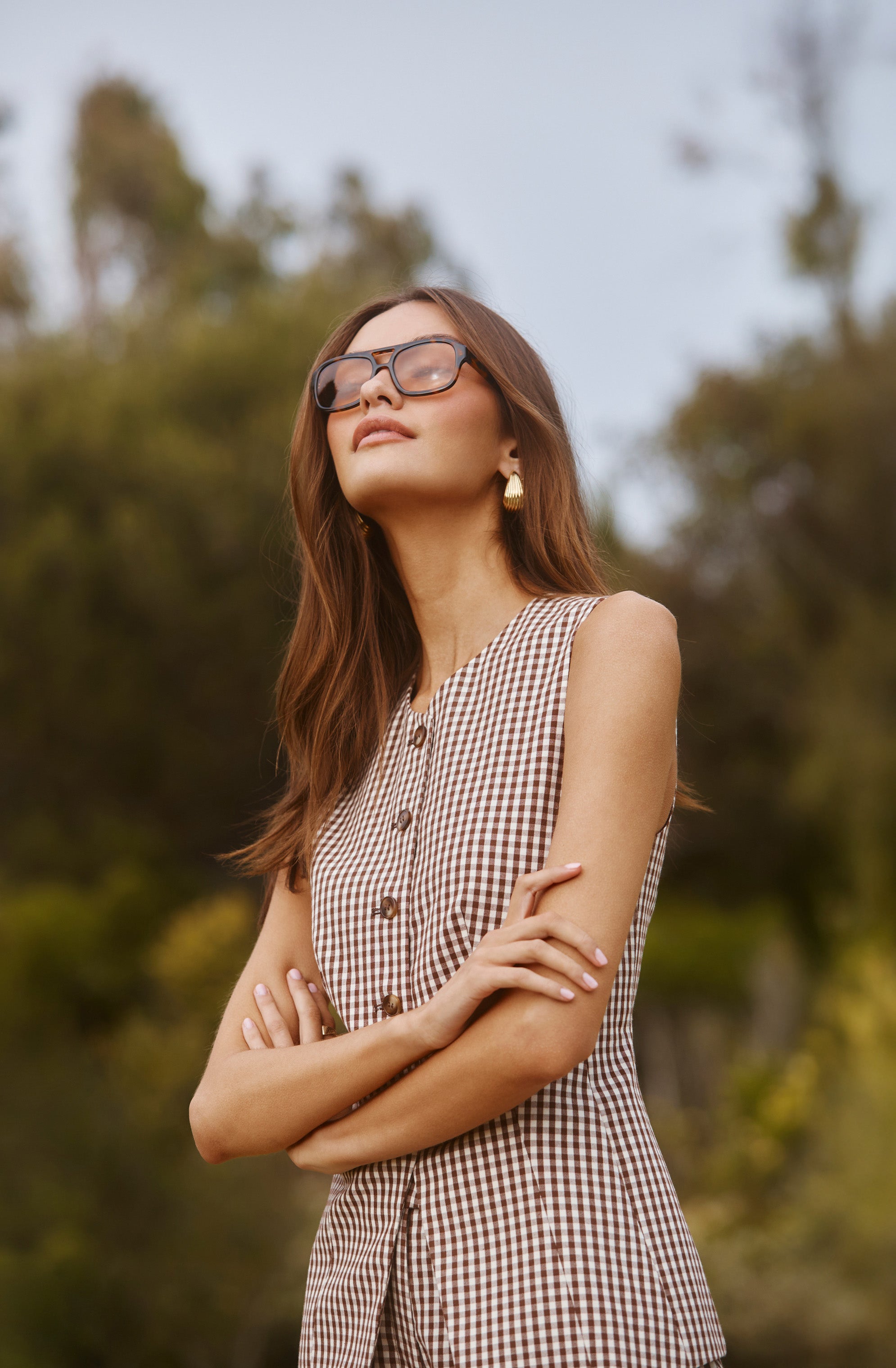 Woman in a sleeveless checkered dress with sunglasses outdoors.