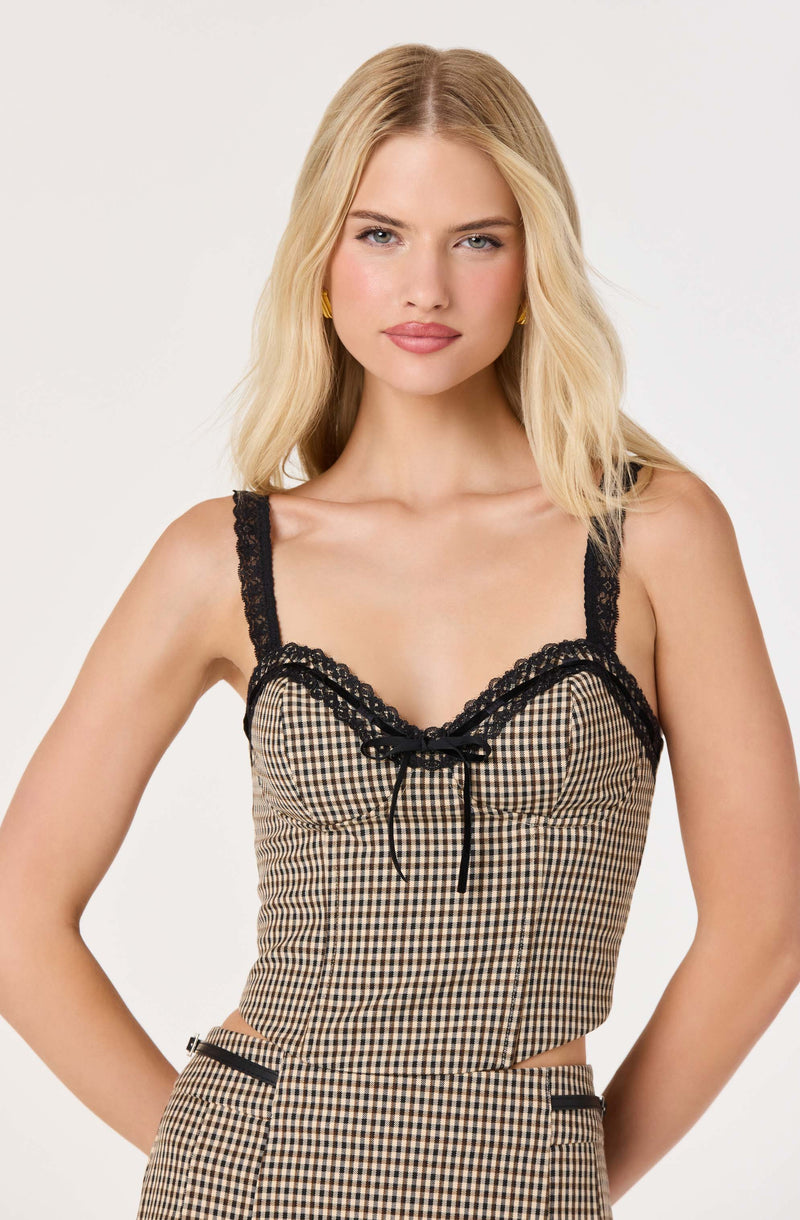 Blonde woman in checkered top with black lace trim and bow, matching checkered pants.