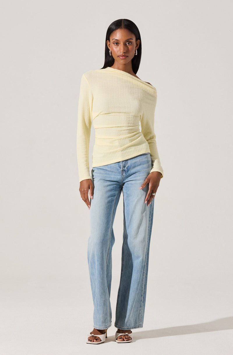 A woman is wearing a light yellow, long-sleeved sweater with a textured fabric and a slightly loose fit. She pairs it with light blue, high-waisted, wide-leg jeans. She is also wearing white, open-toed, heeled sandals with ankle straps.