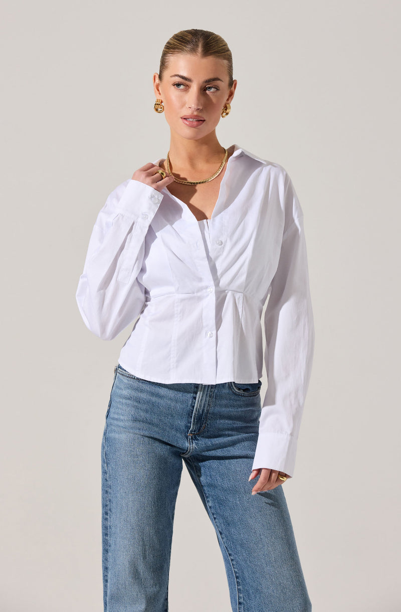 A woman is wearing a white button-up shirt with long sleeves and a collar, paired with light blue jeans.