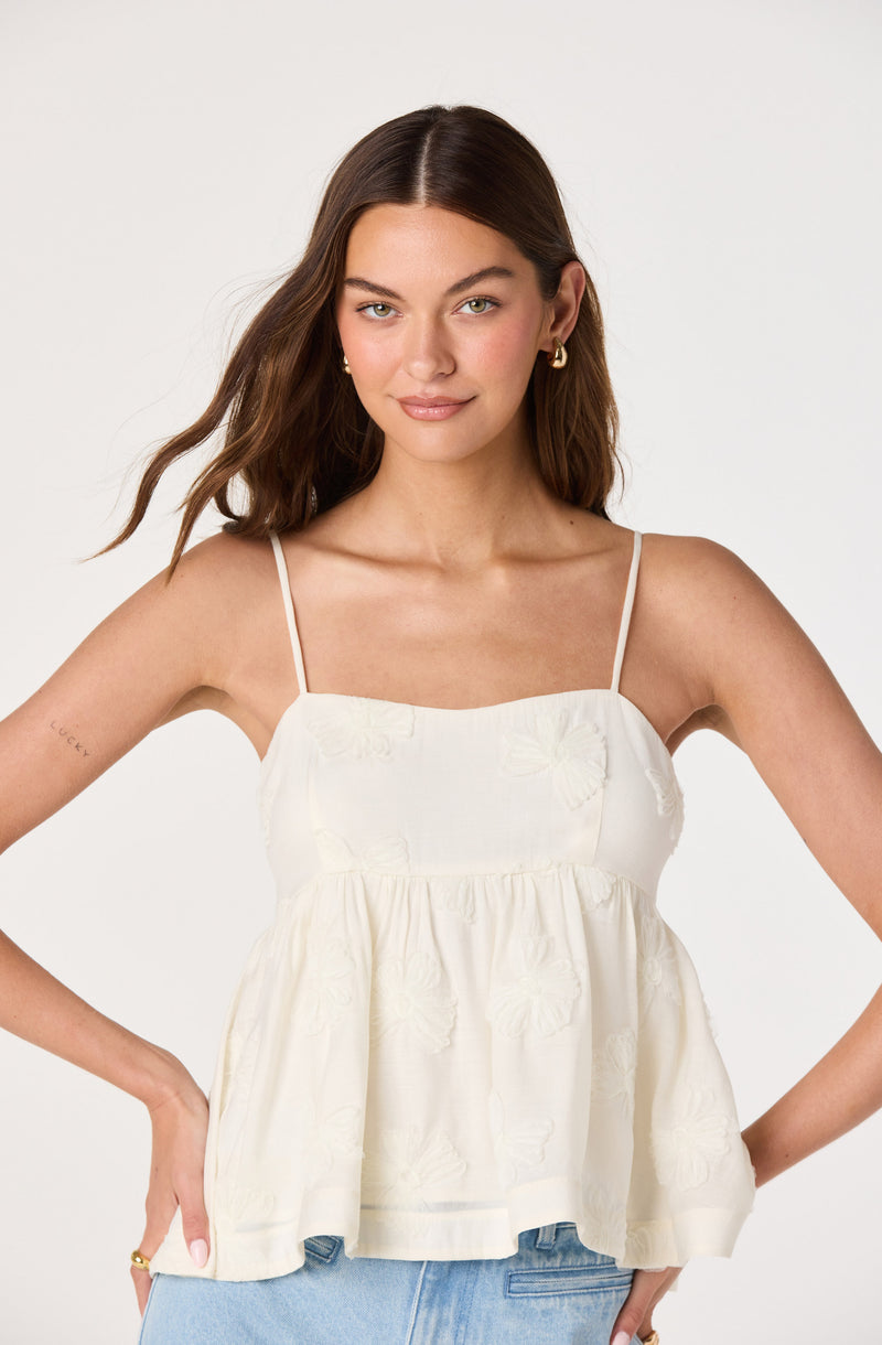 Cream-colored sleeveless top with thin straps and embroidered floral details, loose fit.