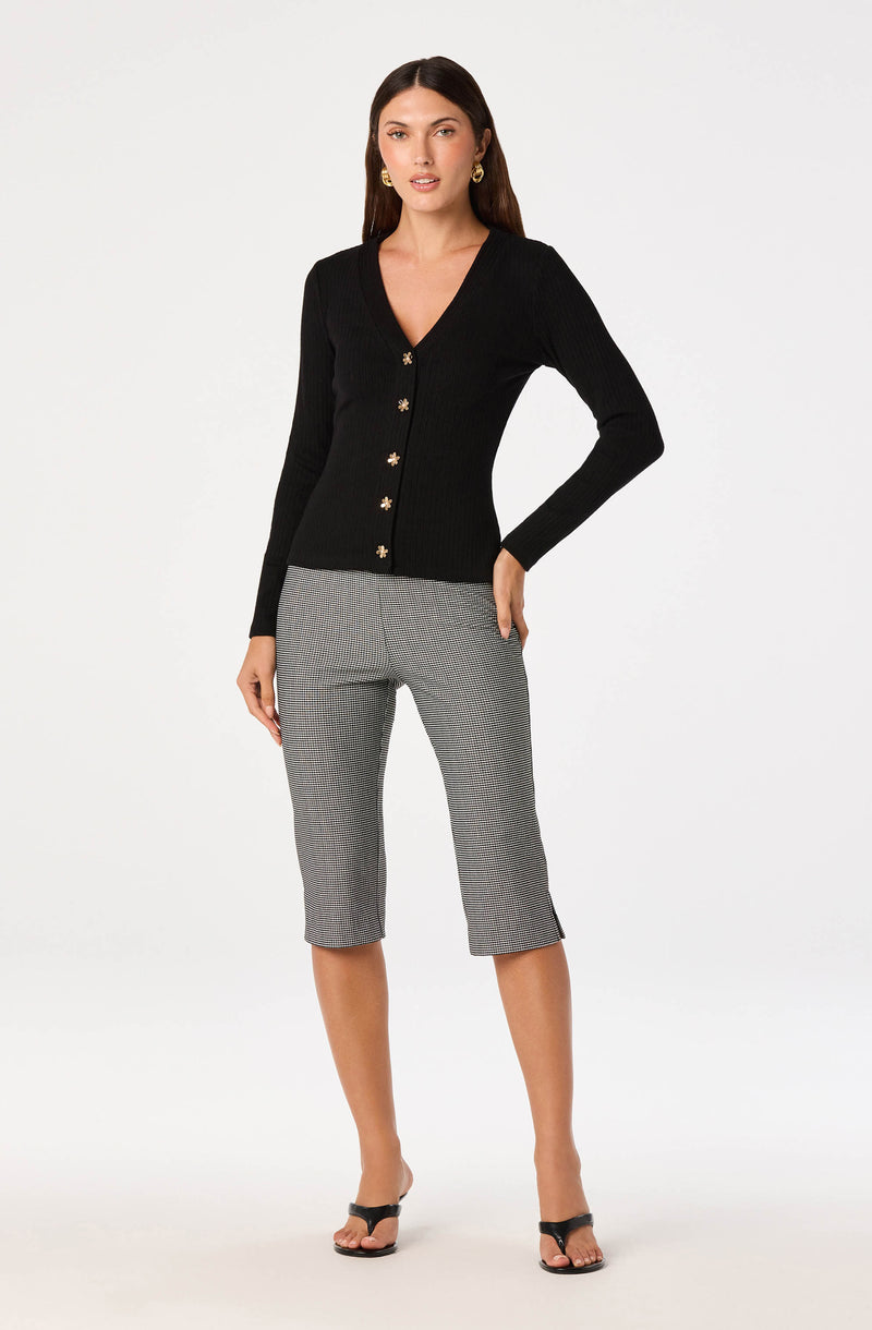 Woman in a black, long-sleeved button-up cardigan with floral buttons, paired with gray cropped pants and black sandals.