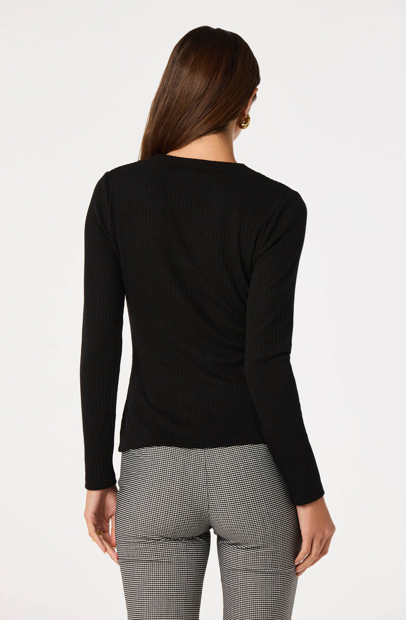 Woman wearing a black ribbed long-sleeve top and checkered black-and-white pants.