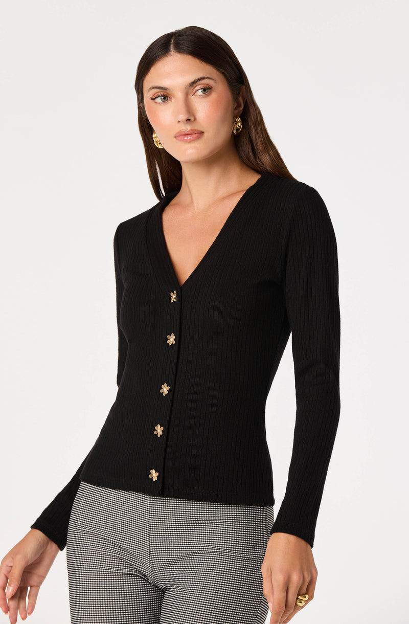 Woman wearing a black, ribbed, V-neck sweater with floral buttons.