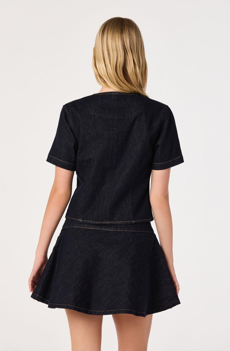 Woman wearing a black denim short-sleeve top and matching black denim skirt.