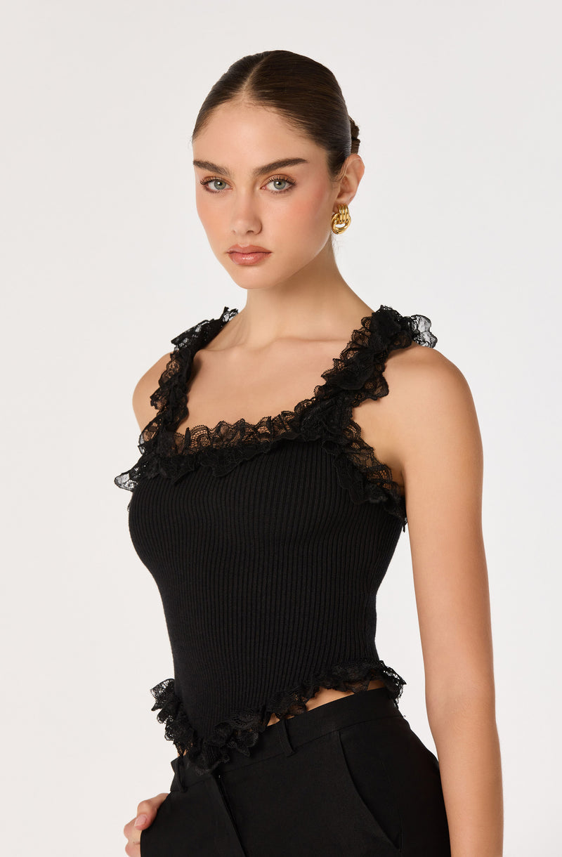 Black sleeveless top with lace ruffle details on the shoulders and hem.