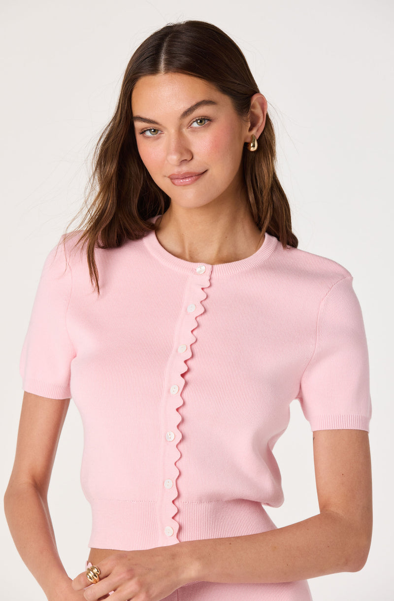 Girl in pink short-sleeve button-up sweater with ruffled front.