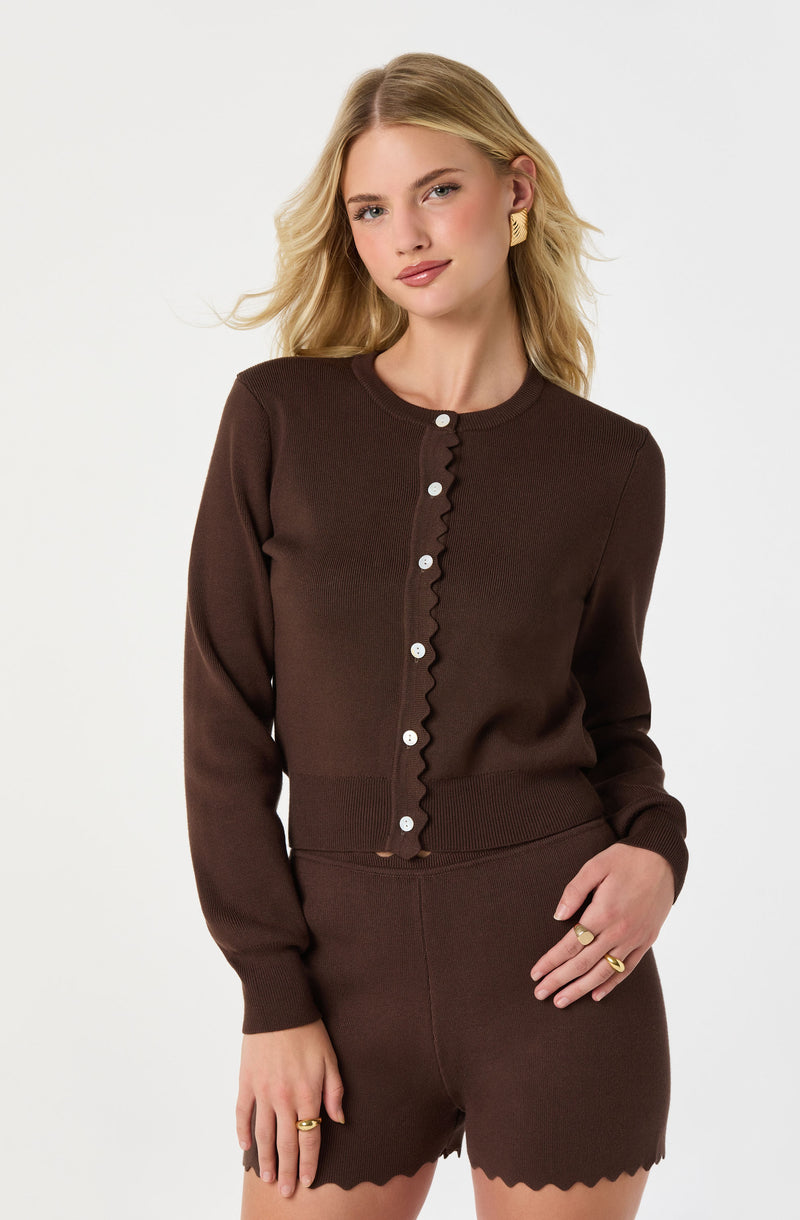 Woman in a brown cardigan and matching shorts, both with scalloped edges.