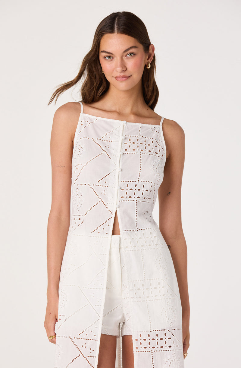 Woman in white eyelet crop top and matching wide-leg pants with cutout details.