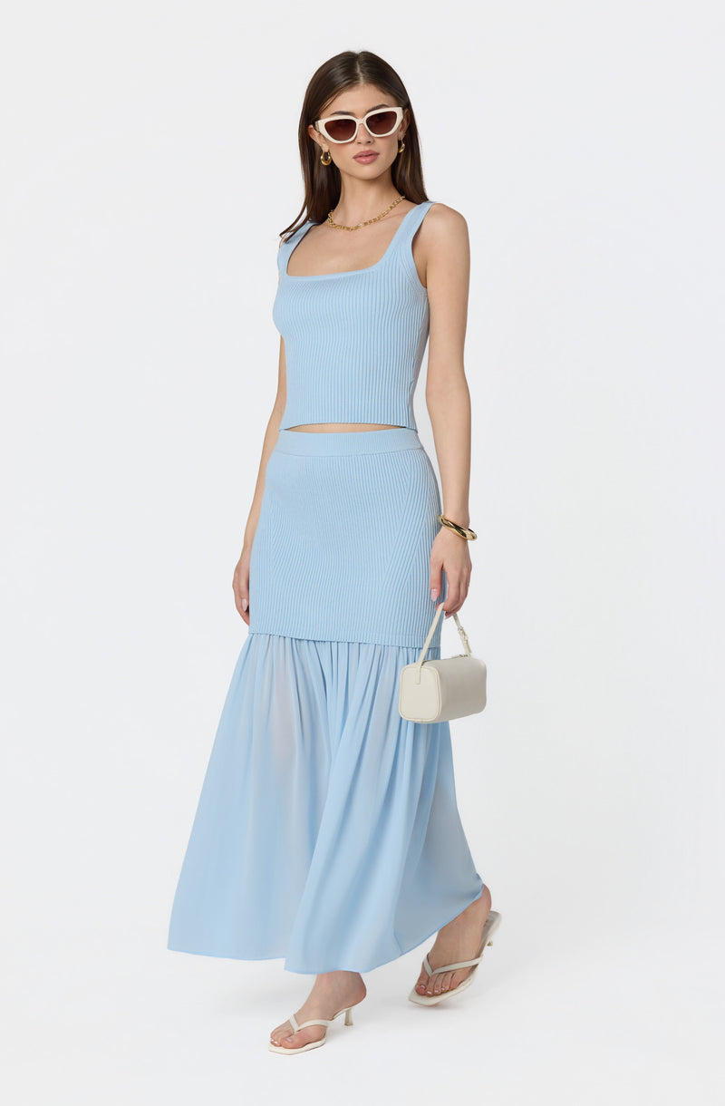 Woman wearing a light blue sleeveless crop top and matching long skirt with ruffled hem.