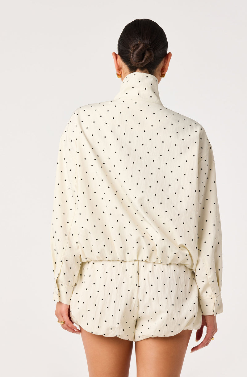 Cream pajama set with black polka dots, long-sleeve top with a high collar, and matching shorts.